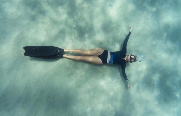 Female freediver lying on the sand bottom