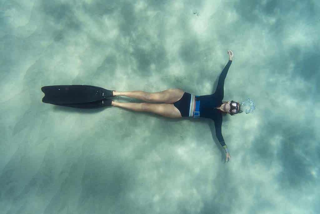 Kobieta freediver leżąca na piaszczystym dnie